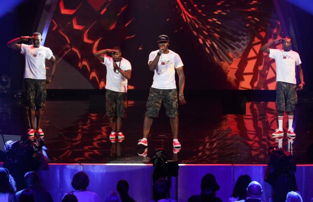 Eine Musikgruppe tritt auf einer Bühne vor Publikum auf.