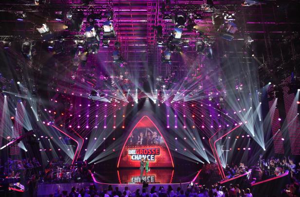 Zwei Moderatoren stehen auf der Bühne von „Die große Chance“ vor Publikum.