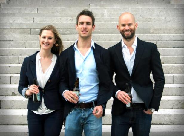 Claudia Simon, Constantin Simon, Alexander Lauber, das Gründer-Team von Nixe Brau und die Kern-Kraft hinter Nixe Bier. (c: nixe brau) Drei Personen stehen auf einer Treppe und halten Bierflaschen.
