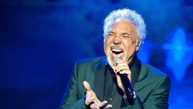 Tom Jones singt mit geschlossenen Augen in ein Mikrofon.