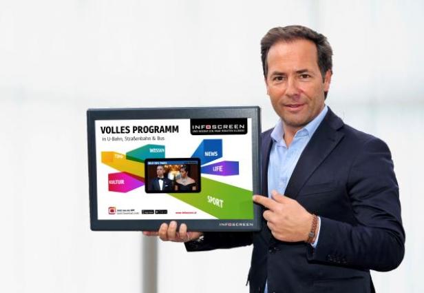 Ein Mann im Anzug präsentiert einen Bildschirm mit dem Infoscreen-Programm.