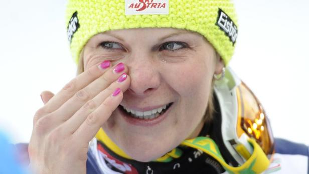 Eine blonde Frau mit Tränen in den Augen und einer gelben Mütze mit der Aufschrift „Ski Austria“.