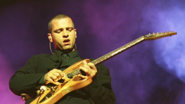 Jovanotti spielt Gitarre während eines Konzerts.