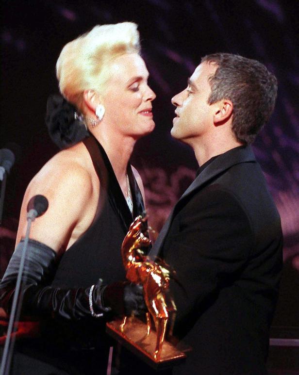 Eine Frau und ein Mann halten eine goldene Bambi-Statue in den Händen.