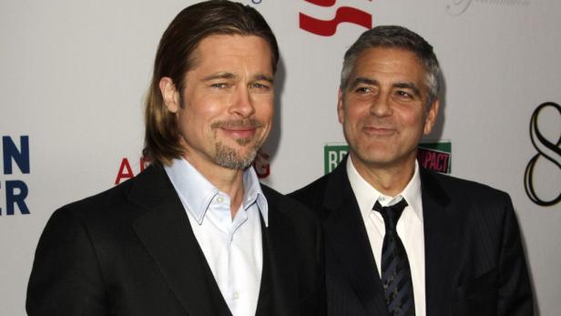 Brad Pitt und George Clooney posieren zusammen auf einem roten Teppich.