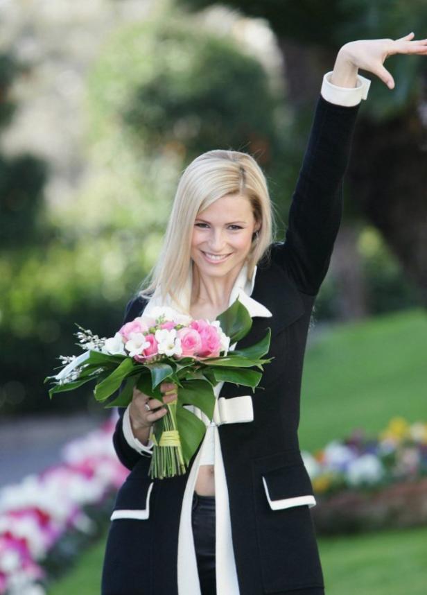 Michelle Hunziker hält einen Blumenstrauß und hebt den Arm.