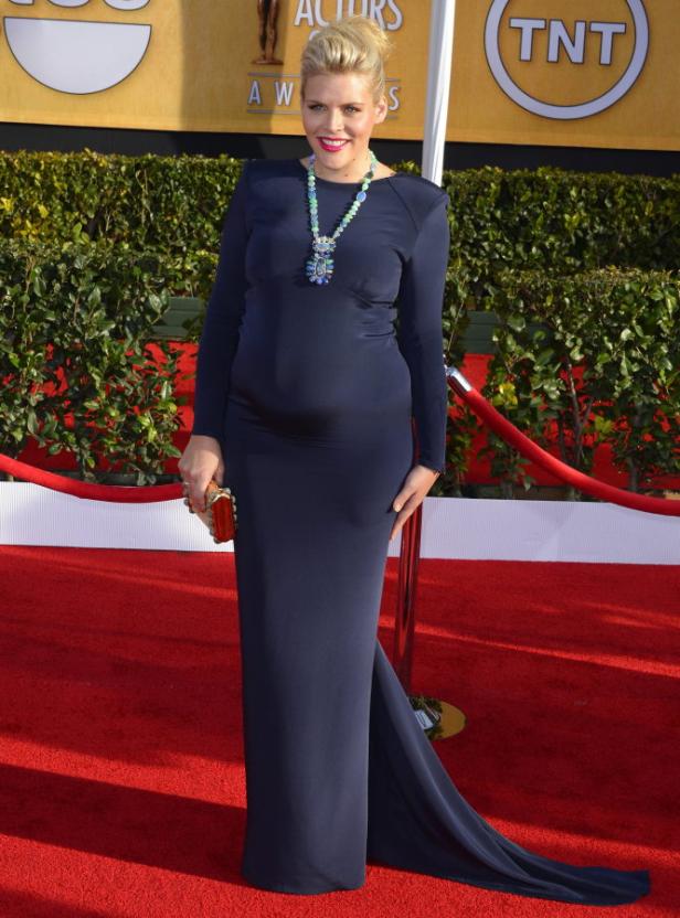 Eine schwangere Frau in einem langen, marineblauen Kleid auf dem roten Teppich.