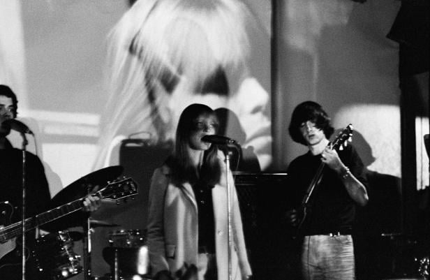 Eine Band tritt in Schwarzweiß vor einer Projektion auf.