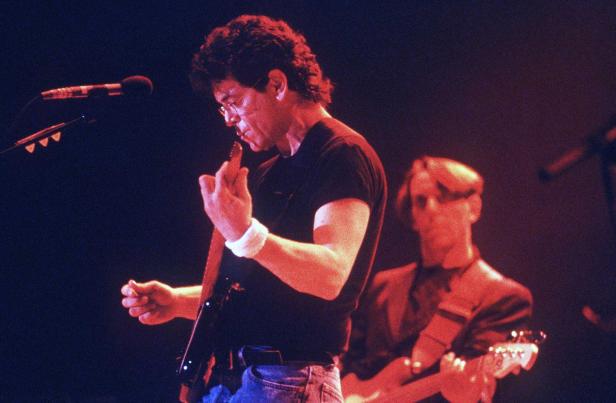 Ein Mann mit Brille spielt Gitarre auf einer Bühne.