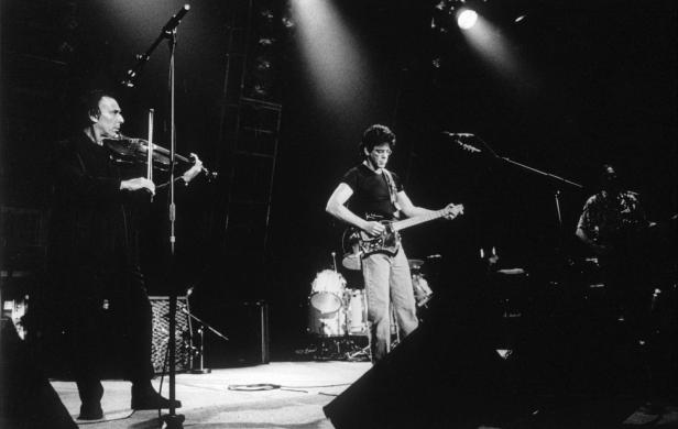 Lou Reed tritt mit einer Band auf einer Bühne auf.