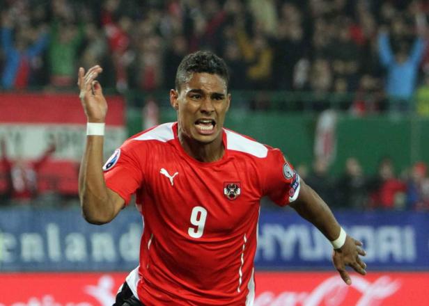 Ein österreichischer Fußballspieler in rotem Trikot mit der Nummer 9 jubelt.