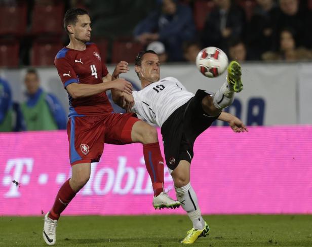 Ein Fußballspieler tritt den Ball, während ein anderer Spieler ihn zu stoppen versucht.