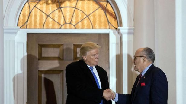 Donald Trump schüttelt Rudy Giuliani die Hand.