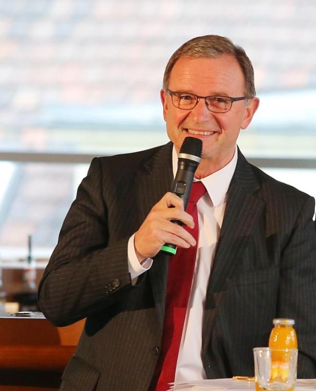 Ein Mann im Anzug spricht in ein Mikrofon.