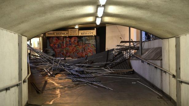 Ein Unterführung ist mit umgestürzten Metallzäunen und Graffiti an den Wänden zu sehen.