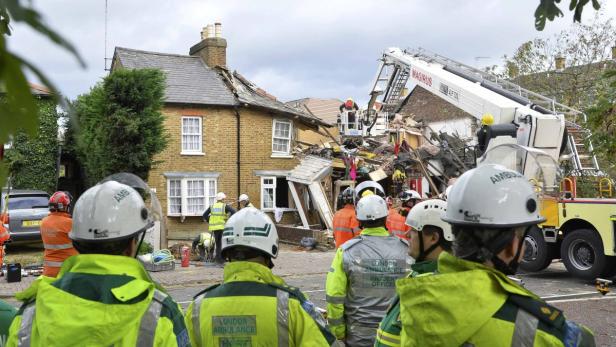 Nach einer Explosion stehen Rettungskräfte vor einem zerstörten Haus.