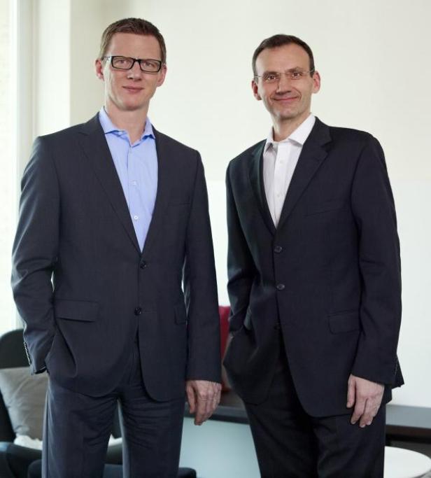 Zwei Männer in Anzügen stehen nebeneinander.