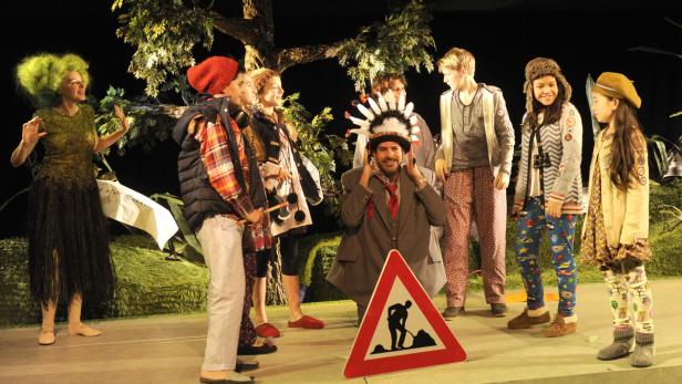 Eine Gruppe von Schauspielern steht auf einer Bühne mit einem „Achtung Bauarbeiten“-Schild.