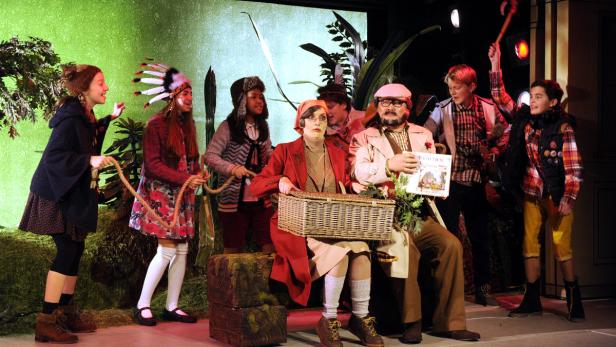 Eine Gruppe von als Waldfiguren verkleideten Kindern auf einer Theaterbühne.