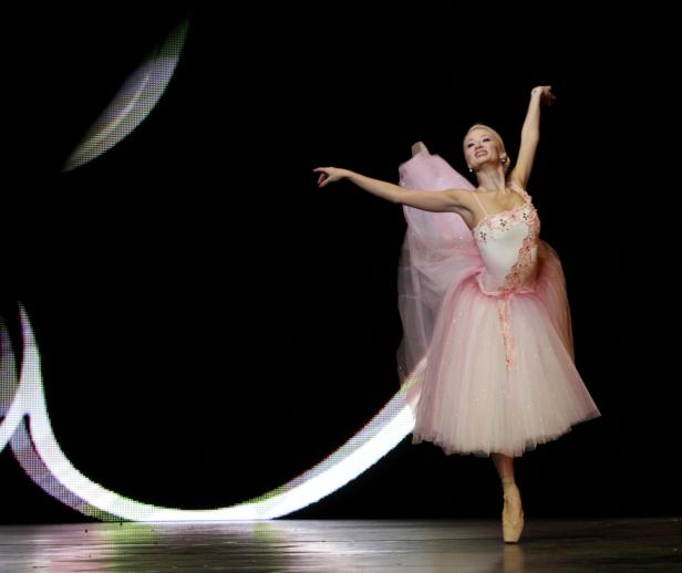 Eine Ballerina in einem rosa Tutu tanzt auf einer Bühne.