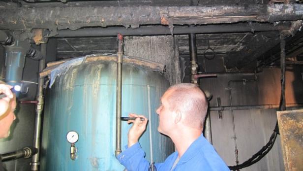 Ein Mann in blauer Arbeitskleidung inspiziert einen großen Tank in einem Maschinenraum.