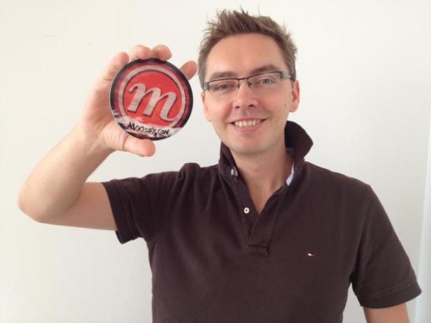 Ein Mann hält einen Aufkleber mit dem Buchstaben „M“ hoch.