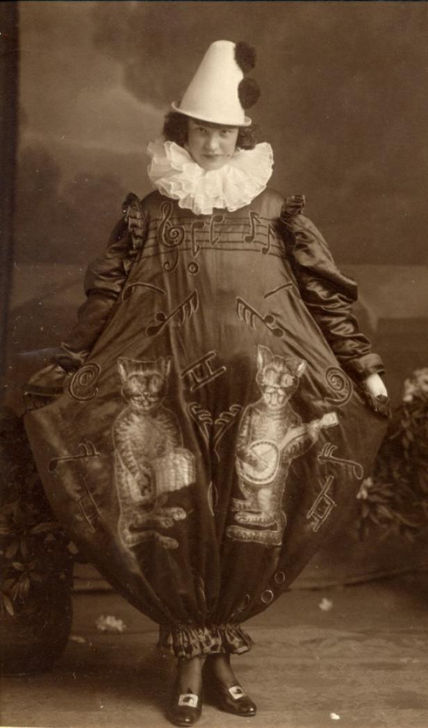 Eine Frau in einem Kostüm mit Noten und Katzen, die Musikinstrumente spielen.