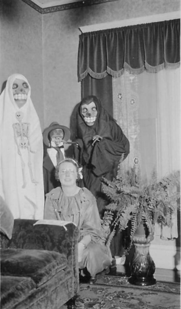 Eine Frau posiert mit drei Personen in gruseligen Halloween-Kostümen.