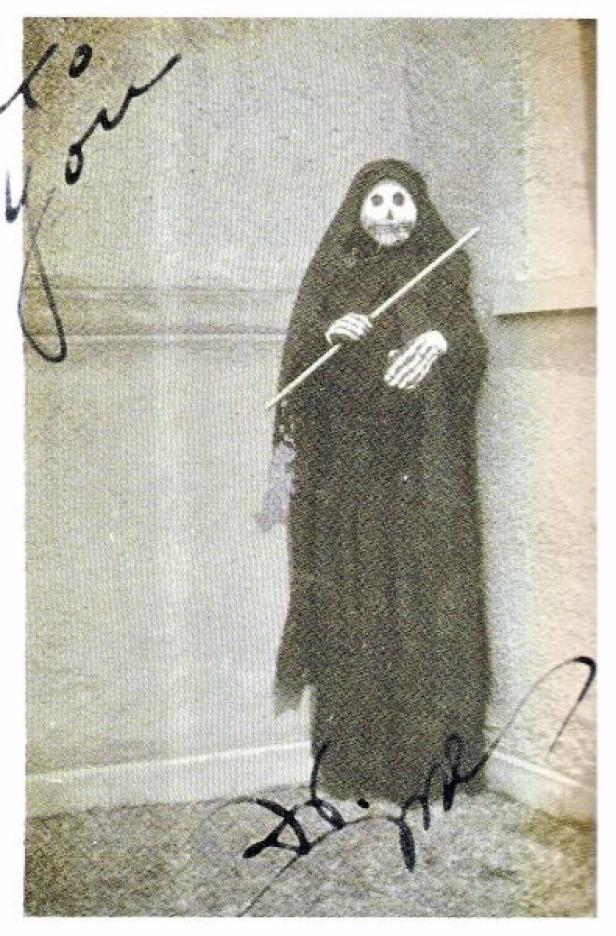 Eine Person in einem Kostüm des Sensenmannes mit einem Stock in der Hand.