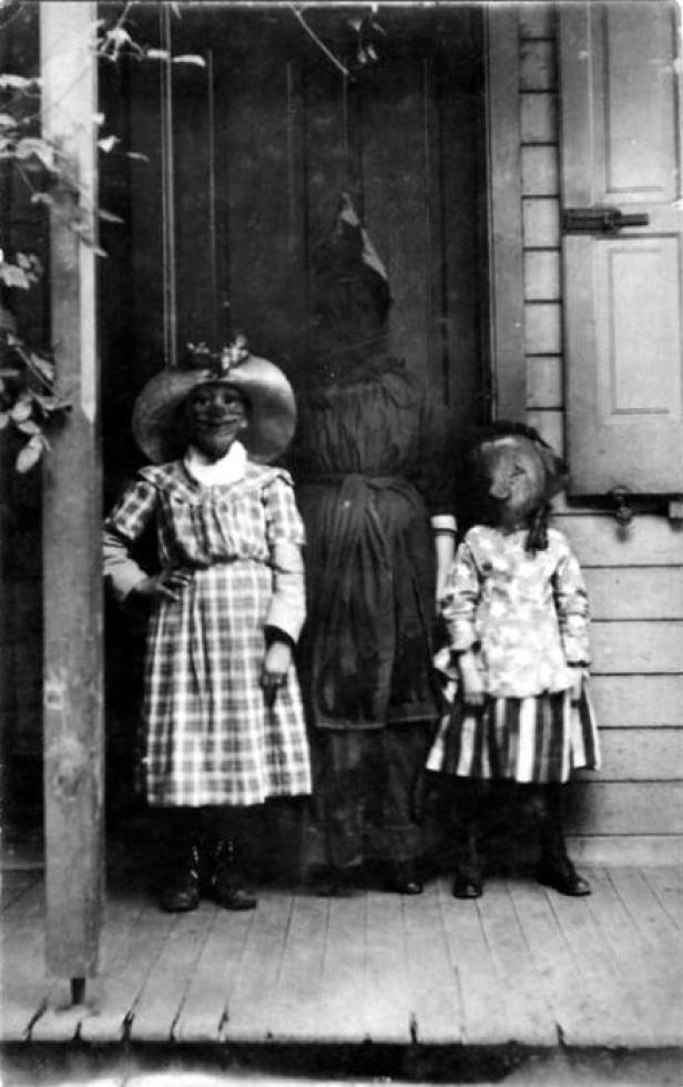 Drei Personen in Kostümen stehen vor einer Haustür.