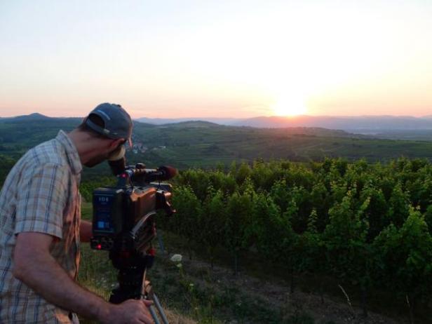 Weine.Winzer.Wege - WeinKultur Österreich - ORF III - Popup Media (c alle Bilder: popup media) Ein Kameramann filmt bei Sonnenuntergang eine Landschaft mit Weinbergen.