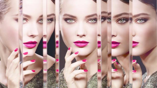Das Gesicht einer Frau mit pinkfarbenem Lippenstift und Nagellack, reflektiert in mehreren Spiegeln.