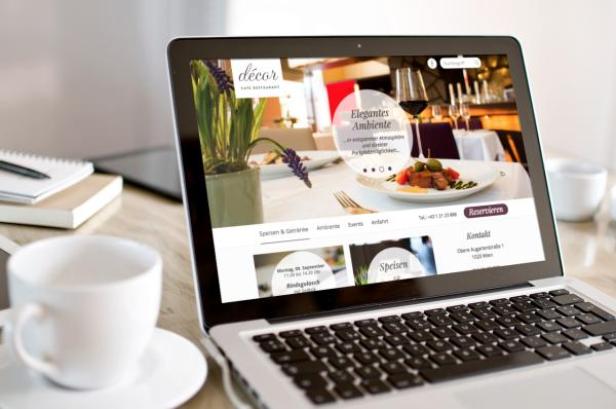 Ein Laptop zeigt die Webseite des Restaurants Décor mit dem Slogan „Elegantes Ambiente“.