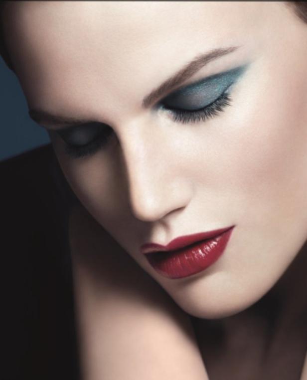 Das Gesicht einer Frau mit blauem Lidschatten und rotem Lippenstift.