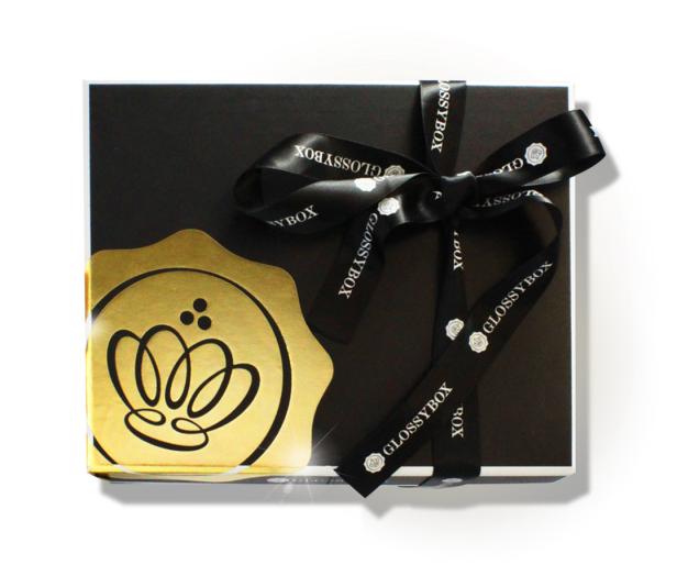 Eine schwarze Glossybox mit goldener Banderole und Schleife.