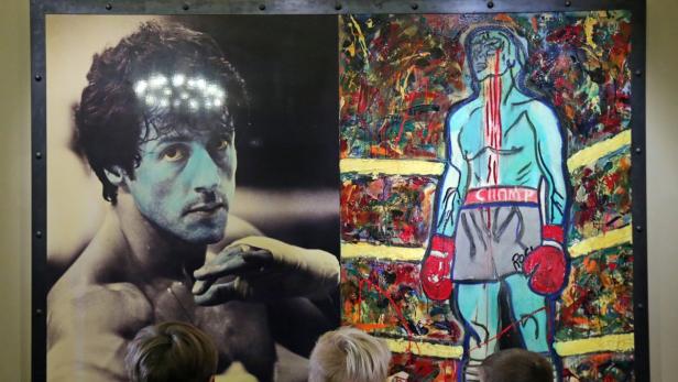Ein zusammengesetztes Bild zeigt ein Porträt von Sylvester Stallone und ein Gemälde eines Boxers.