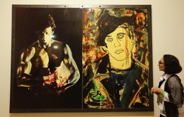 Eine Frau betrachtet ein zweiteiliges Gemälde von Sylvester Stallone als Rocky.