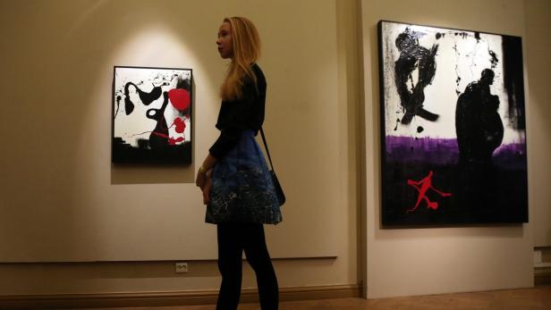 Eine junge Frau betrachtet zwei abstrakte Gemälde in einer Galerie.