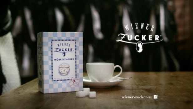 Eine Packung Wiener Würfelzucker, eine Tasse und Zuckerwürfel auf einem Tisch.