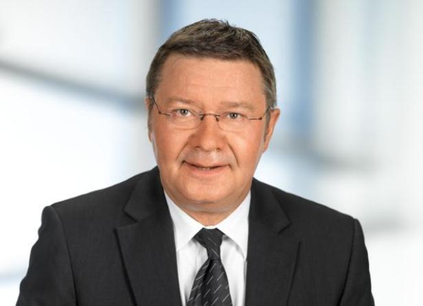 Ein Mann mit Brille und Anzug blickt in die Kamera.