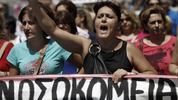 Frauen demonstrieren mit einem Banner, auf dem „Krankenhäuser“ steht.