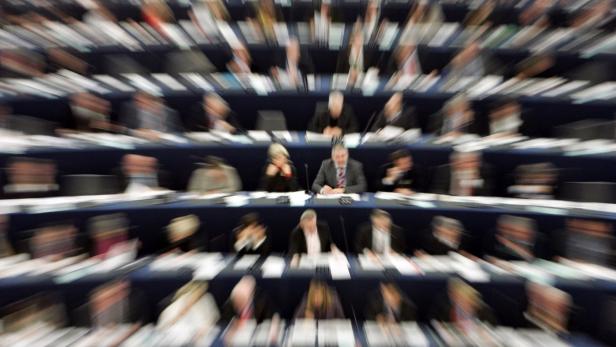 Viele Menschen sitzen in einem großen Saal an Tischen.