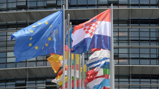 Die Europaflagge und die kroatische Flagge wehen vor einem modernen Gebäude.