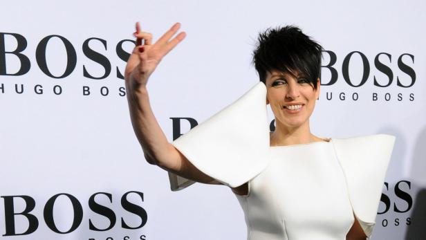 Eine Frau in einem weißen Kleid posiert vor einem „Hugo Boss“-Hintergrund.