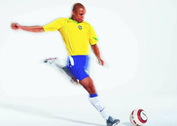 Ein Fußballspieler im brasilianischen Nationaltrikot schießt einen Ball.