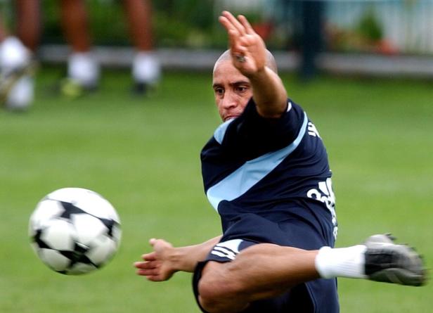 Roberto Carlos schießt einen Fußball auf einem grünen Rasen.