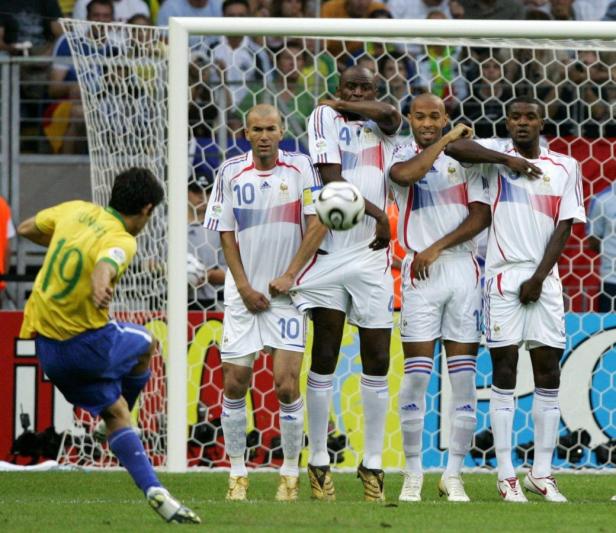 Ein brasilianischer Fußballspieler schießt einen Freistoß auf die französische Mauer mit Zidane.