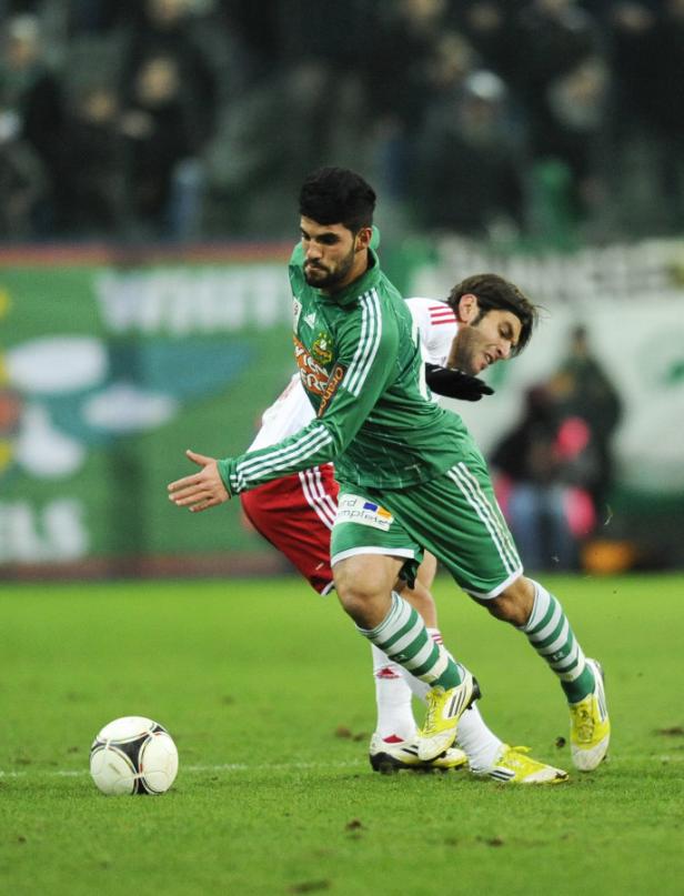 Ein Fußballspieler in Grün versucht, den Ball zu erreichen.