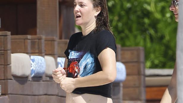 Drew Barrymore steht mit nassem Haar und einem T-Shirt am Pool.
