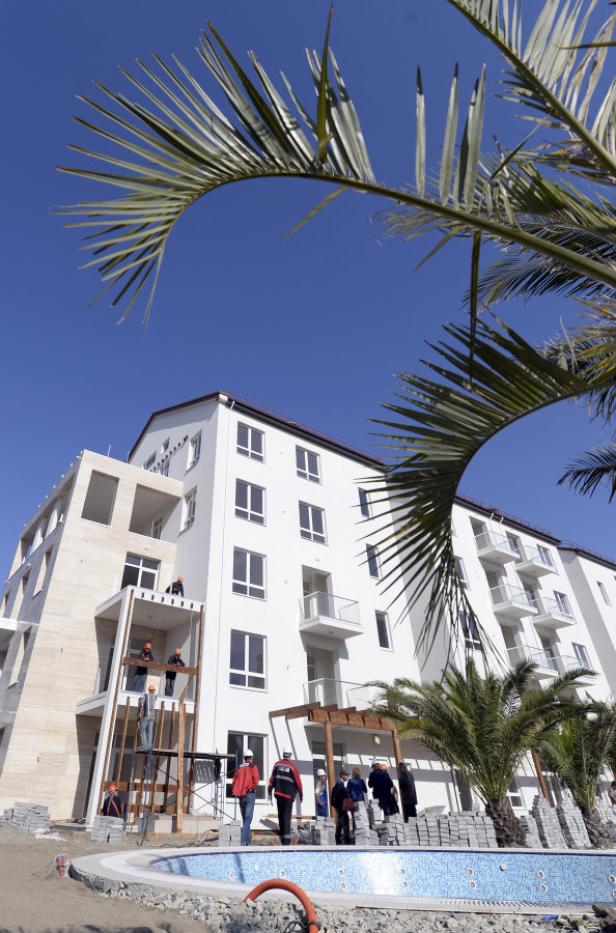 Bauarbeiter arbeiten an einem neuen Hotel mit Pool und Palmen.